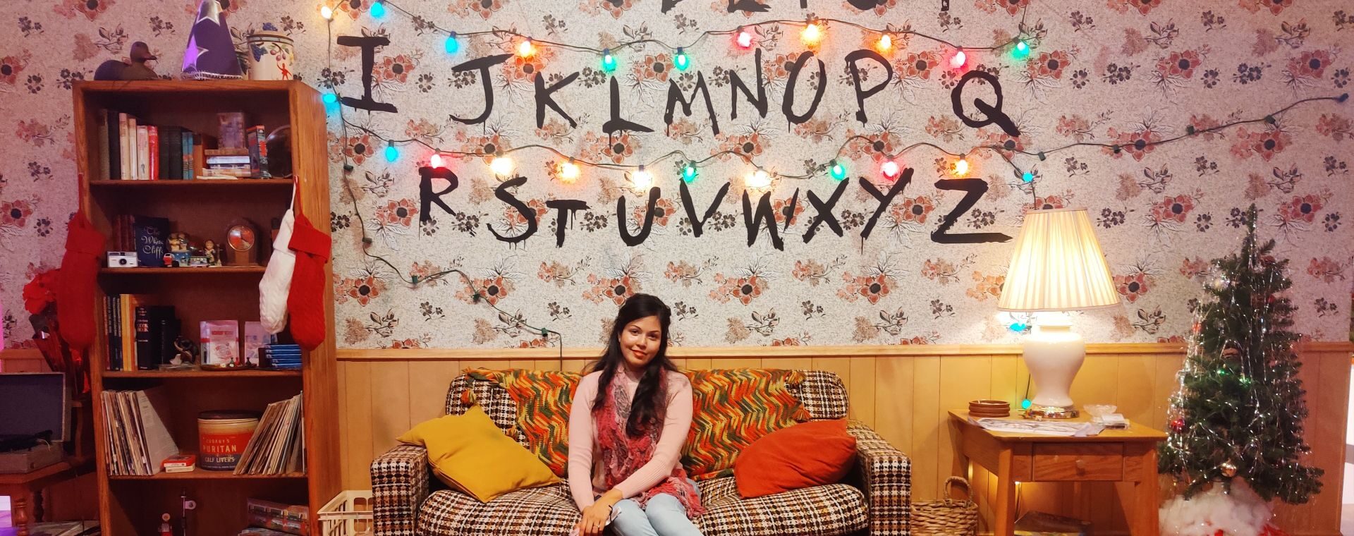 Girl sitting on couch of Stranger Things Living Room Replica